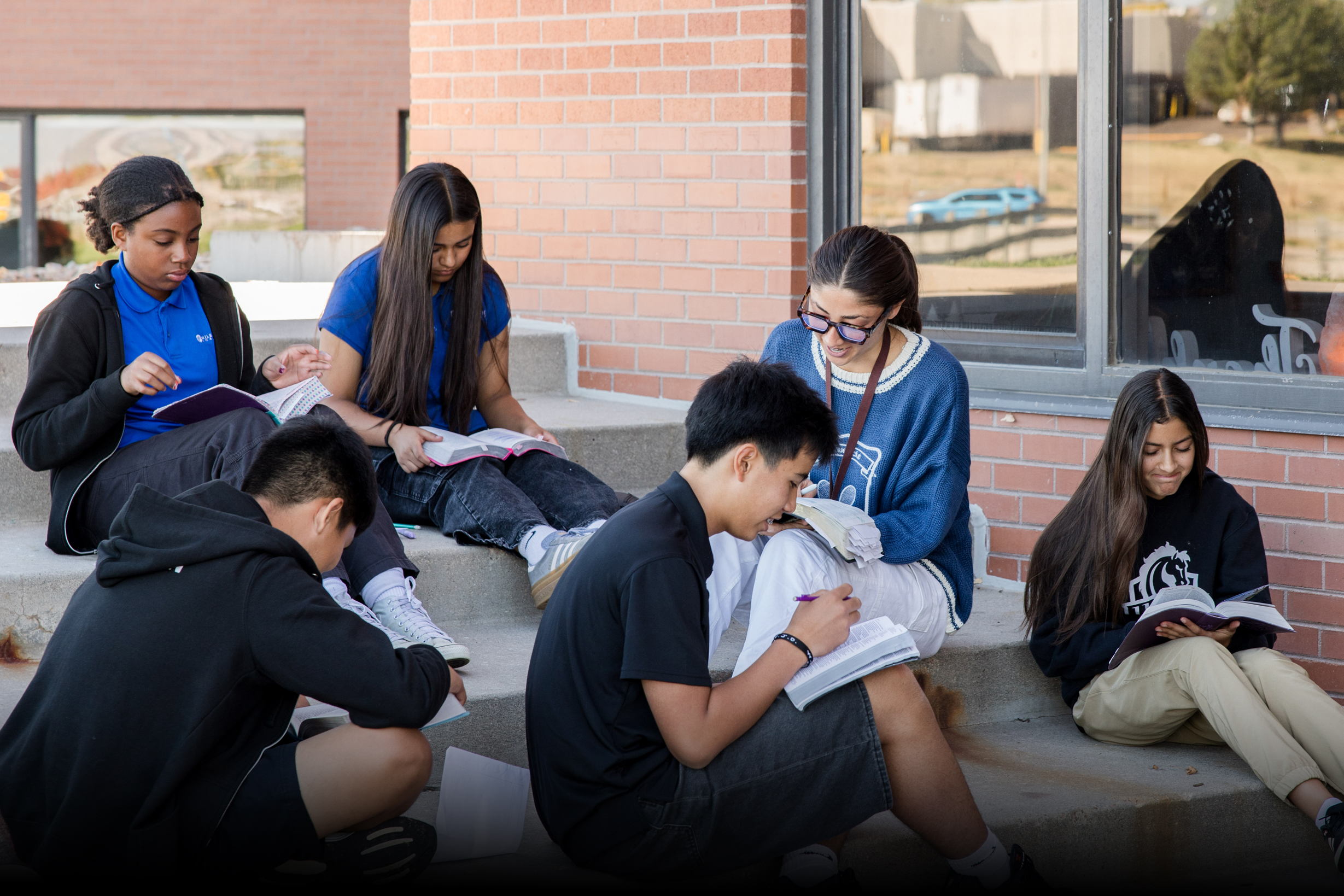 Middle School students studying Bible outside with their teacher.